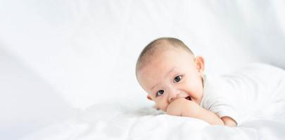 lycklig familj, söt asiatisk nyfödd pojke liggande lek på vit säng titta på kameran med ett skrattande leende lyckligt ansikte. lite oskyldigt nytt spädbarn bedårande barn i första dagen i livet. mors dag koncept. foto