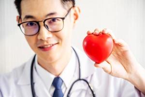 läkare med stetoskop visar rött hjärta på sjukhuskontoret, medicinsk hälsovård och läkare personal service koncept. foto