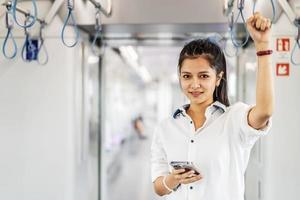 ung asiatisk kvinna passagerare står och använder mobiltelefon inuti tom tunnelbana eller sky train bil, fritid och dagliga liv foto