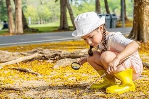 bild av söt tjej som utforskar naturen med förstoringsglas utomhus, barn som leker i skogen med förstoringsglas. nyfiken unge söker med förstoringsglas på gräset i parken foto