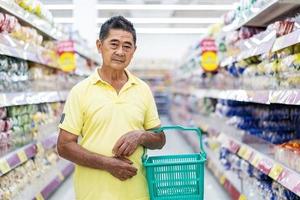 asiatisk senior man shopping i en stormarknad, äldre kund med en varukorg i en stormarknad foto