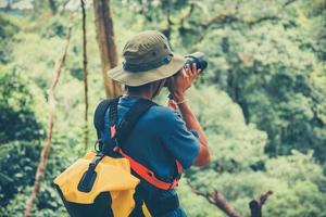 utomhusäventyr och resenär man håller kameran på naturskog turist på semester semesterresor äventyrlig backpacking resevandring - man fotograf tar foto moderna utomhusutflykter