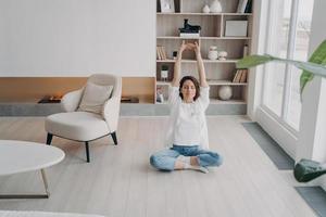 flickan gör stretchövningar på golvet hemma. glad kvinna mediterar med slutna ögon. foto