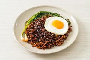 torkade koreanska kryddiga svarta sås snabbnudlar med stekt ägg och kimchi foto