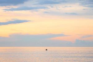 silhoutte av romantiska par simmar på mitten av havet under dramatisk solnedgång himlen. negativt rymdfoto foto