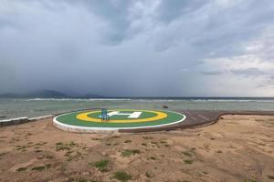 grönt helikopterdäcksskylt för privat vid stranden av orten under dyster himmel. foto