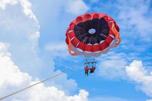 parasailing under den blå himlen på tropiska öar. roliga semesteraktiviteter. kopiera utrymme för turism och kärleksrelationer foto