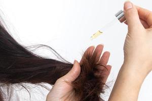 en ung kvinna med långt hår och en pipett i handen. hårbehandling och vård foto