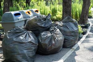 plast papperskorgen påsar med sopor på trottoaren i parken, ren miljö koncept. foto