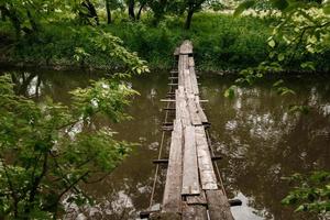 gammal träbro, träbro över en liten flod, bro med naturen. foto