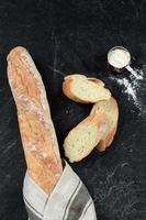 färskt baguette bröd på trä bakgrund. hemlagad fransk två baguettelimpor och skivor foto