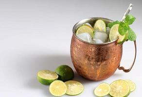 moscow mule iskall cocktail i koppar kopp med lime och och mint vit bordsbakgrund foto