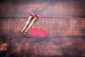 pappershjärtan och röda rosor på trägolv foto