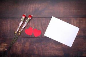 pappershjärta med röda rosor och vitt papper på trägolv för design och alla hjärtans dag foto