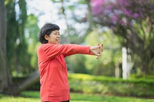 senior asiatisk kvinna kroppsuppvärmning innan träning. gammal kvinna stretching innan jogging i trädgården, sport idrottare kör koncept. foto