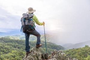 aktiva klättrare njuta av utsikten.kvinnlig backpacker med ryggsäck och kryckor njuta av solskenet på berget, kopiera utrymme. foto