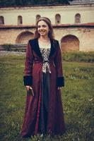 porträtt av brunett kvinna klädd i historiska barockkläder med gammaldags frisyr, utomhus. foto