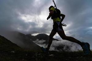 extrem bergsloppstävling skymarathon. atlet springer med stavar i ryggsäcken foto