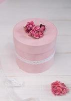 vacker rosa rund presentförpackning är dekorerad med avsmalnande rosor. romantiskt förpackningskoncept foto