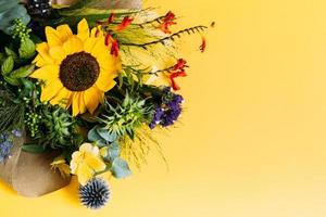 vacker bukett blommor med en solros på en ljusgul bakgrund med kopia utrymme. foto