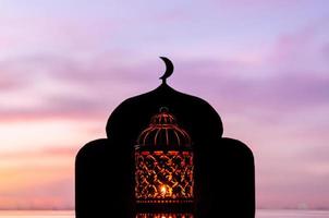 lykta med suddigt fokus på moskébakgrund som har månsymbol på toppen och gryningshimlen. foto