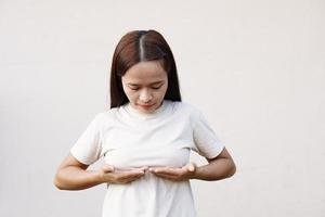 asiatisk kvinna trycker hennes bröst med handen foto