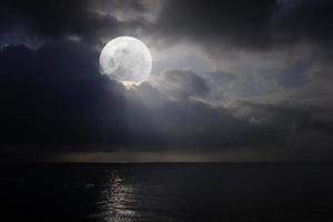 romantiskt och naturskönt panorama med fullmåne på havet på natten. foto