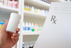 kvinnlig farmaceut med recept och medicinflaska på apoteket foto