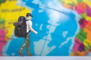 miniatyr människor resenär med ryggsäck på världen bakgrund foto