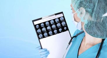 en läkare i medicinska kläder och blå medicinska handskar undersöker en uppsättning MR-skanningar av ett barns hjärna i ett laboratorium. kopieringsutrymme. foto