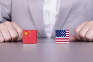 USA, Kinas handelskrig, intressekonflikt. flaggor av Amerika och Kina på träkuber på bakgrunden av en affärsman. affärsstrategi. foto
