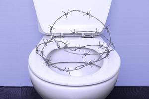 vit toalettskål med öppet lock och hjärtformad taggtråd på svart klinkergolv och lila väggar. proktologi medicinskt koncept. foto
