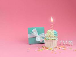 söt cupcake med rosett ljus och presentförpackning på rosa bakgrund med kopia utrymme. grattis på födelsedagen part bakgrund koncept. foto