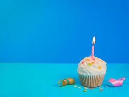 grattis på födelsedagen cupcake och rosett ljus på blå bakgrund med kopia utrymme. foto