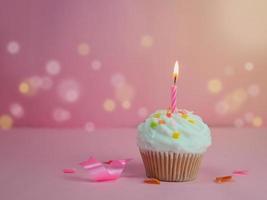 grattis på födelsedagen cupcake och rosett ljus på rosa bakgrund med kopia utrymme. foto