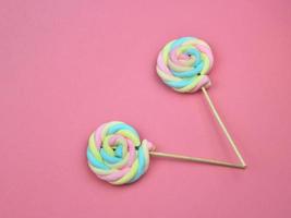 färgglada regnbåge färg maräng lollipop godis på rosa bakgrund. söt sommar söt dessert koncept. foto