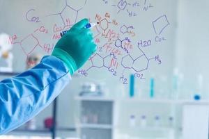 forskarna, kemister, forskare upptäcker den kemiska formeln skriver på whiteboard i laboratoriet. forskaren upptäcker vaccin eller läkemedel för behandlingspatienter infekterade med covid19. foto