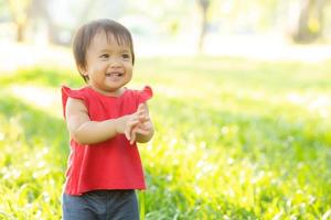 porträtt ansikte av söt asiatisk liten flicka och barn lycka och kul i parken på sommaren, le och glad från asien barn och koppla av i trädgården, livsstil barndom koncept. foto
