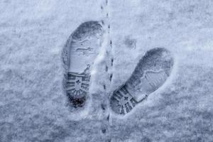 fotspår av manliga skor i ny vit snö på vintern foto