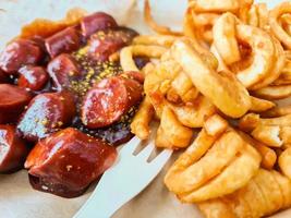 selektiv fokusering. traditionell tysk currywurst, serverad med chips på en tallrik foto