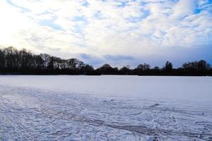 utsikt över en frusen sjö under vintern med massor av skridskobanor. foto