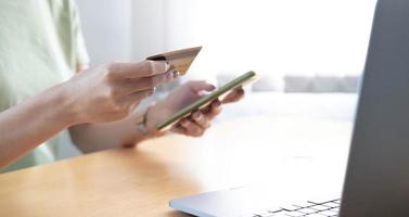 närbild av en kvinna som håller kreditkort i handen gör online shopping med smart telefon foto