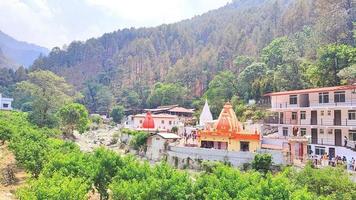 kainchi dham uttarakhand heliga tempel är omgivet av kullar och träd och en flod som rinner bredvid den. foto