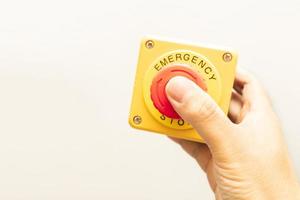 stoppknappen och arbetarens hand håller på att trycka på den. nödstopp knapp. stor röd nödknapp eller stoppknapp för manuell tryckning. foto