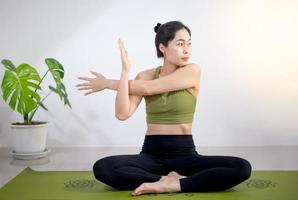 kvinna som gör yoga på den gröna yogamattan för att meditera och träna i hemmet. foto