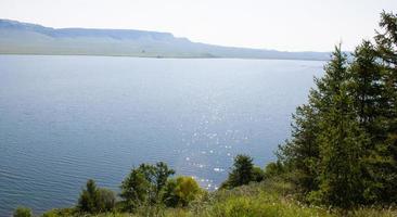 en stor sjö bland träd och berg en sommardag. foto