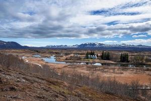 avlägsen vy av hus mitt i bäcken och dramatiskt landskap mot molnig himmel foto