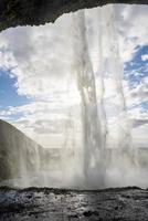 majestätiska seljalandsfoss med dimma som flödar från berget mot blå himmel foto