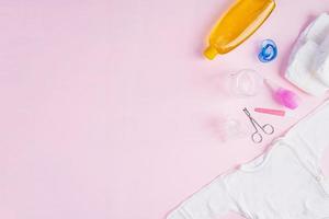 babykläder och andra saker för barn på rosa bakgrund. nyfödd baby koncept. toppvy foto