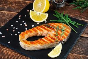 grillad laxfisk på stenbräda. salt atlantisk lax stekt på grill med citron foto